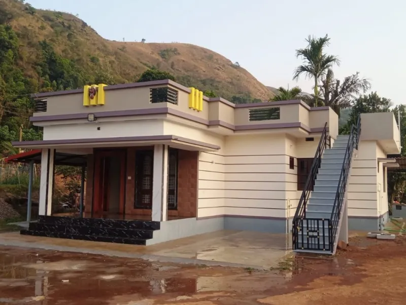 Single-storey house with stairs to an open terrace, set against a hillside in the Kudremukh foothills