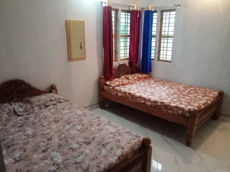 Bedroom with two wooden double beds and windows with curtains
