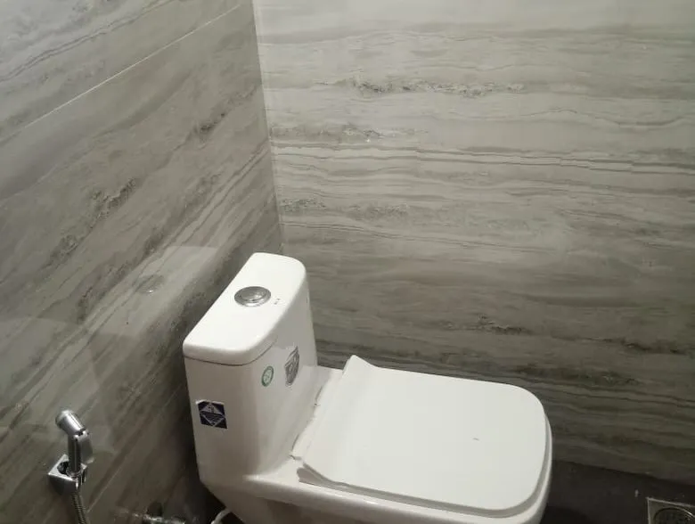 Bathroom with grey tiled walls and a western toilet