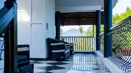 Upper-floor balcony with chequered floor, wicker chairs and a view of the hills