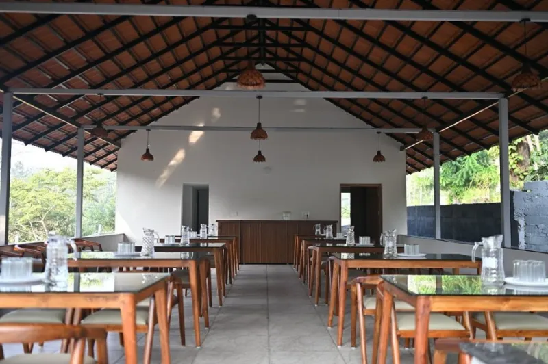 Open-sided dining hall with wooden tables under a tiled roof