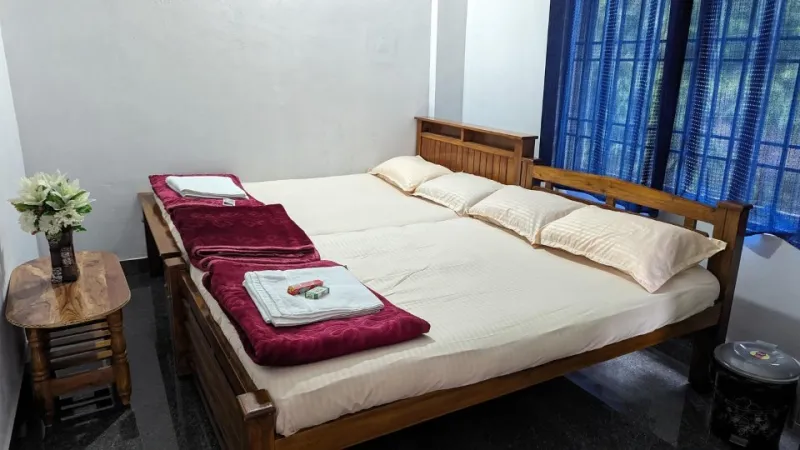 Room with joined double beds, fresh towels and a wooden side table