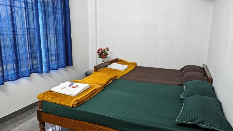 Room with joined beds in green and brown linen and blue curtains