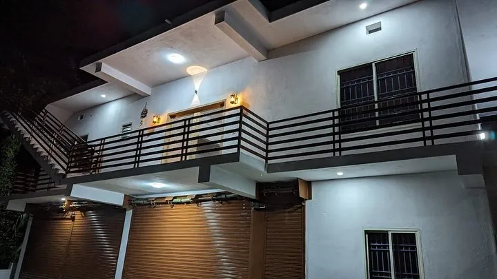 Two-storey building with a long upper balcony, lit at night