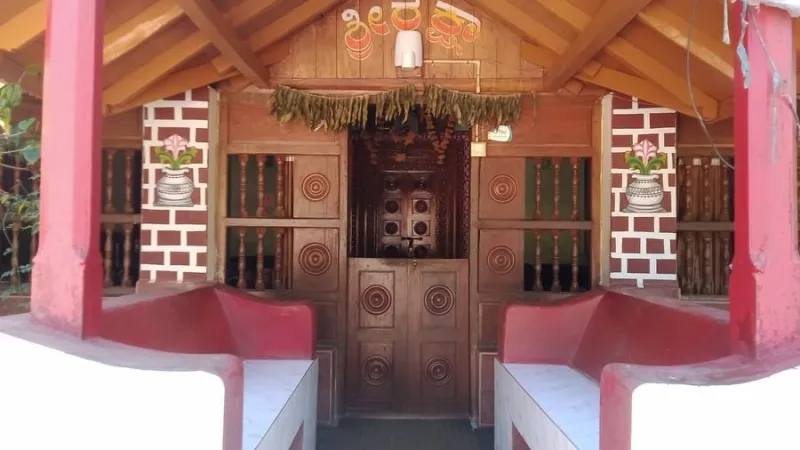 Cottage entrance with a carved wooden door, red pillars and built-in benches