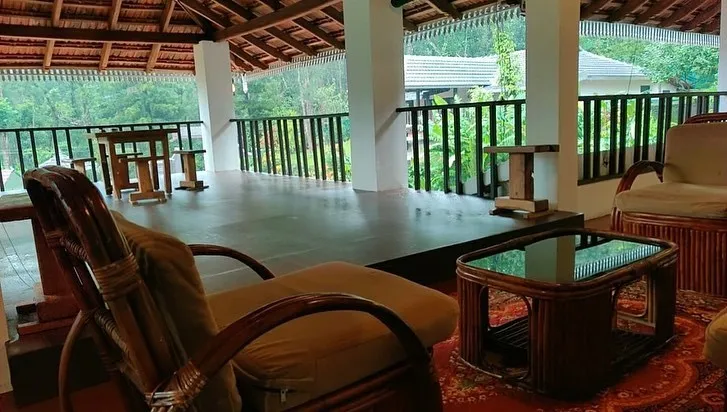 Covered upper verandah with cane chairs and a view of the trees