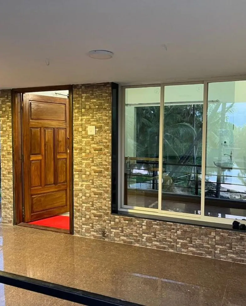Upper-floor entrance with a wooden door and a large window onto the palms