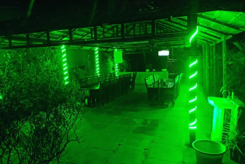 Open-air dining area with long tables, lit up at night