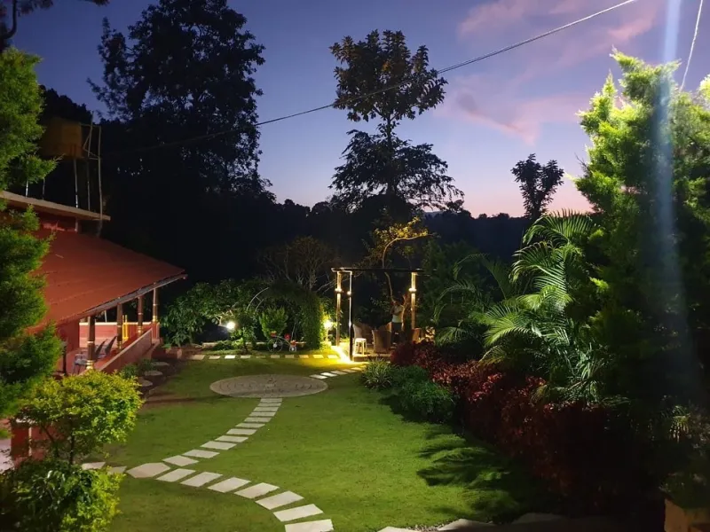 Lit garden with a stepping-stone path and a gazebo at dusk