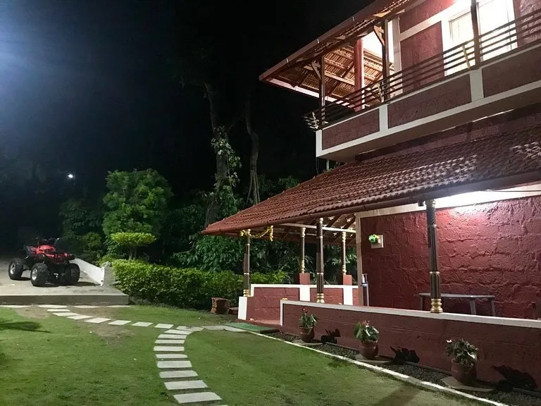 Two-storey villa with tiled roofs and a lawn, lit at night
